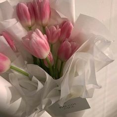 a bouquet of pink tulips wrapped in white paper