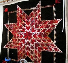 a red and black quilted star hanging on a wall next to a sewing machine