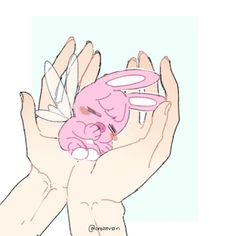 two hands holding a pink toy in the shape of a human head with wings on it