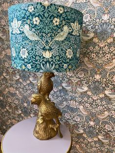 a lamp that is sitting on top of a white table next to a wallpapered wall