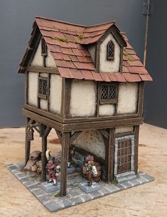 a miniature model of a house with people standing in front of it on a table