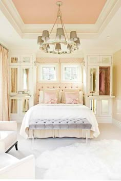 a white bed sitting in a bedroom under a chandelier