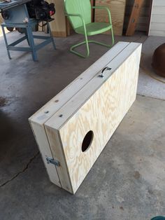 a wooden box sitting on top of a floor next to a green chair and table