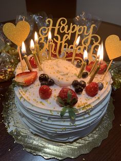 a birthday cake with candles and strawberries on it