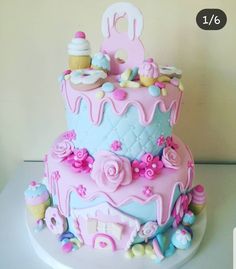 there is a pink and blue cake with decorations on the top tier, sitting on a table