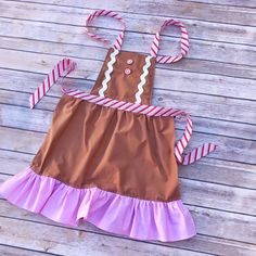 a brown and pink dress with candy canes on the bottom is sitting on a wooden floor