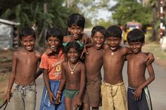 a group of young boys standing next to each other on the side of a road