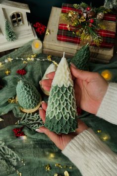 a person holding a small green christmas tree in their hand next to some other decorations