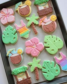 decorated cookies in the shape of palm trees, beach scenes and coconuts on a baking sheet