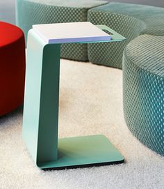 a small table sitting on top of a white floor next to two colorful chairs and ottomans