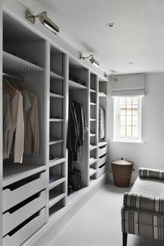 a walk in closet filled with lots of white shelves and clothes on top of it