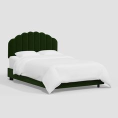 a bed with a green velvet headboard and white linens on the bottom, in front of a gray background