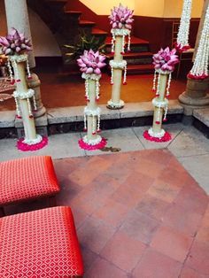 some pink flowers are hanging from the ceiling in front of red benches and pillars with pearls on them