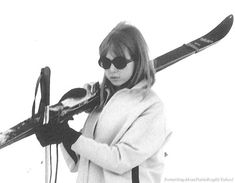 a woman holding skis while standing next to a pole