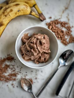 a bowl filled with chocolate ice cream next to two bananas