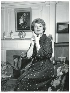 an old photo of a woman sitting on a chair in front of a fire place