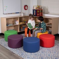 two children sitting on colorful stools in a play room with toys and bookshelves