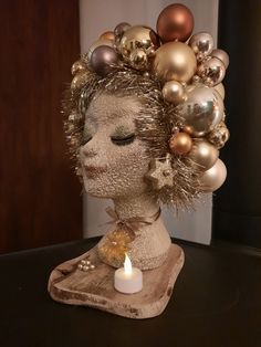 a candle is lit in front of a sculpture of a woman with ornaments on her head