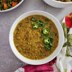 two bowls filled with different types of food on top of a white table cloth next to other dishes