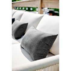 two gray and white pillows sitting on top of a white couch next to each other