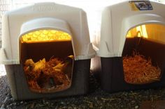 two white and black litter boxes with hay inside them on the ground next to a fence