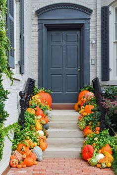 pumpkins and gourds line the front steps of a house