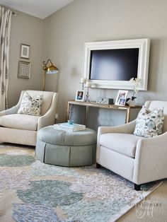 a living room with two chairs and a television on the wall above it, in front of a window