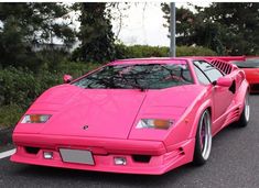 two pink sports cars parked next to each other