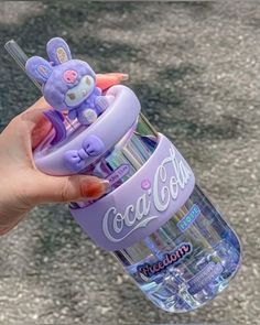 a hand holding a purple cup filled with toothbrushes and a stuffed animal in it