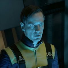 a man in a yellow and black outfit looking at something with blue light on his face