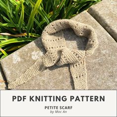 a knitted scarf laying on top of a stone slab in the grass with text overlay that reads, pdf knitting pattern