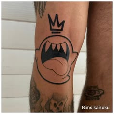 two men's legs with tattoos on them, one has a crown and the other has an angry face