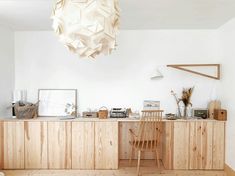 a white room with wooden furniture and a large light fixture hanging from the ceiling above it