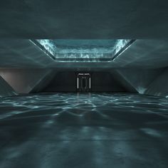 an empty room with light coming through the opening in the ceiling and water on the floor