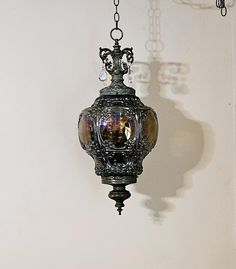 an ornate light fixture hanging from a chain in a room with white walls and chandelier