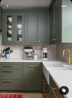 a kitchen with green cabinets and gold pulls on the cupboards is pictured in this image