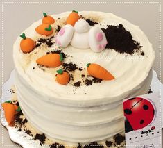 a cake decorated with carrots and an animal figure on the top is frosted in white icing