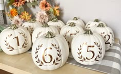 white pumpkins with gold numbers on them sitting on a table