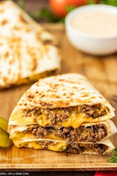 two quesadillas cut in half on a cutting board with pickles next to them