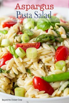 pasta salad with asparagus and tomatoes in a white bowl