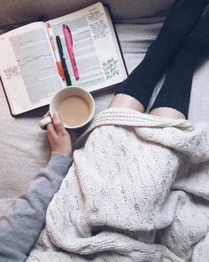 a person laying on a couch with a book and cup of coffee