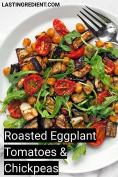 roasted eggplant, tomatoes and chickpeas on a white plate with a fork