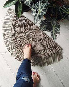 a woman's feet standing on a rug next to plants and potted plants