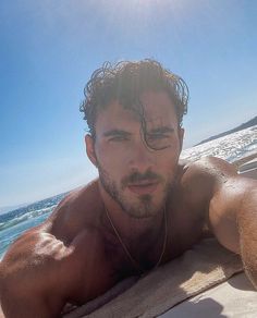 a shirtless man laying on top of a boat in the ocean with his head tilted