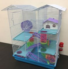 a bird cage that is sitting on the floor next to a wall with toys in it