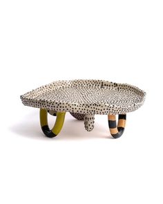 a white and black polka dot tray with two legs on each side, sitting in front of a white background