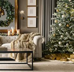 a living room decorated for christmas with a white couch and tree in the corner next to it