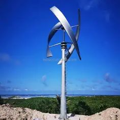 a large metal wind turbine sitting on top of a sandy beach