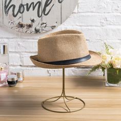 a hat is sitting on a stand next to a vase with flowers and perfumes