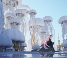 a person standing in front of some jellyfish like structures with their reflection on the water